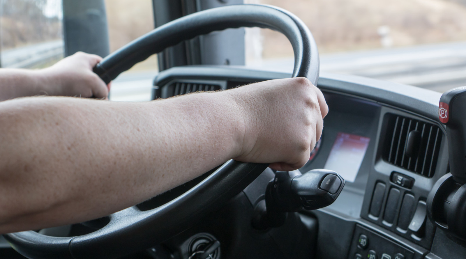 Zwei Hände umfassen das Lenkrad eines Lkw