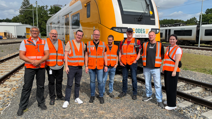 Die Trainfluencer posieren vor einem Zug der ODEG.